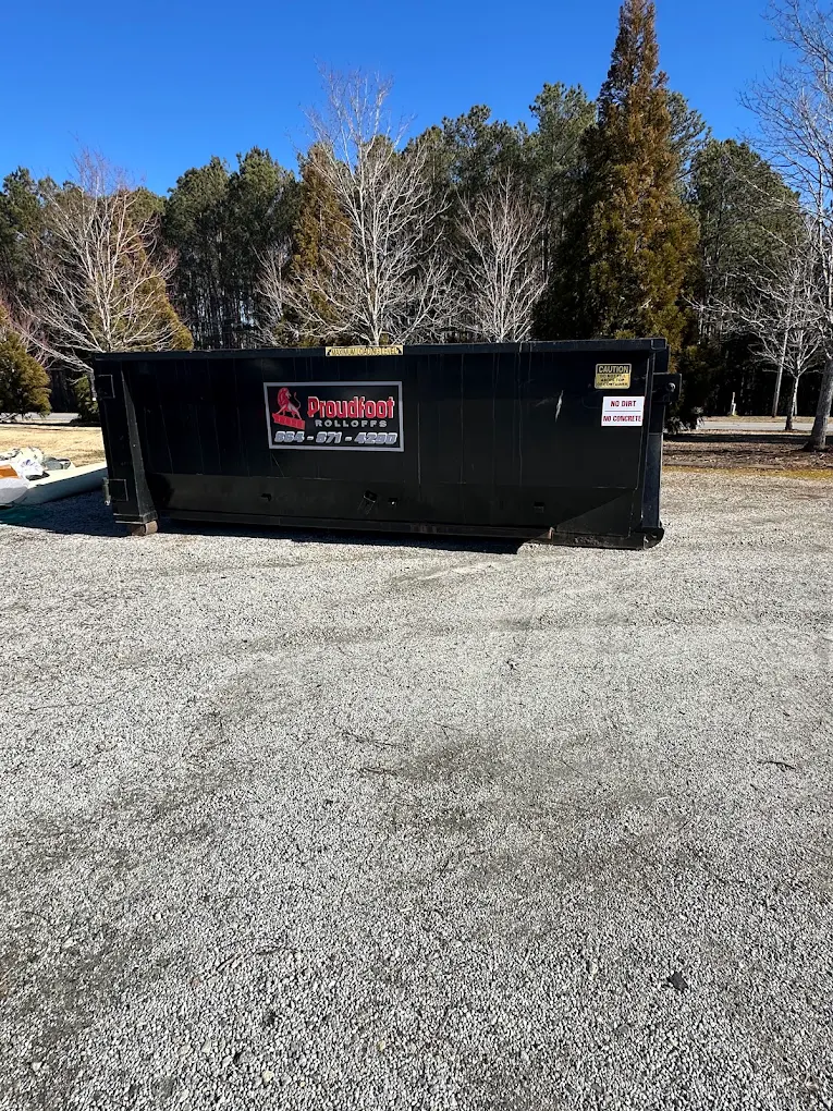Black Proudfoot roll-off dumpster staged on a gravel lot