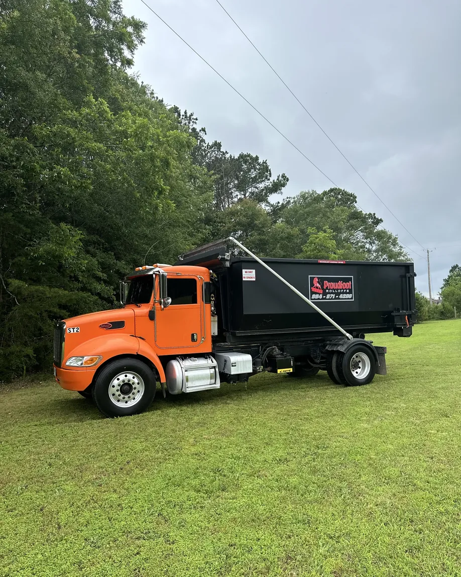 A Proudfoot Rolloffs dumpster on the truck with the lion logo and phone number on the side