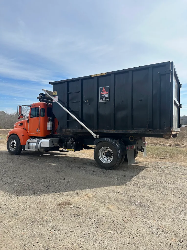 Proudfoot Rolloffs truck loading a roll-off dumpster on a contractor job site